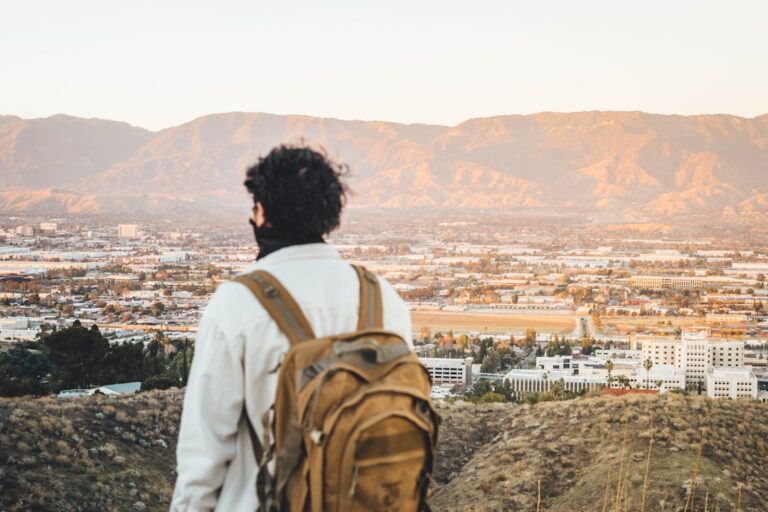 Man with backpack standing on a mountain, illustrating independence, perspective and building a self-directed life