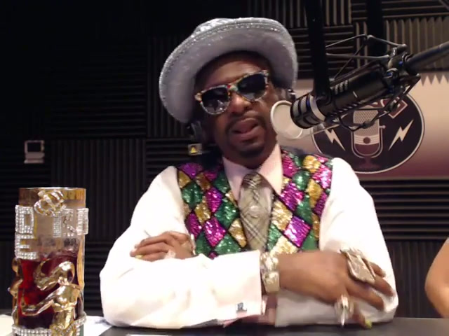 Bishop Don Magic Juan speaking into a microphone in a colorful sequined vest