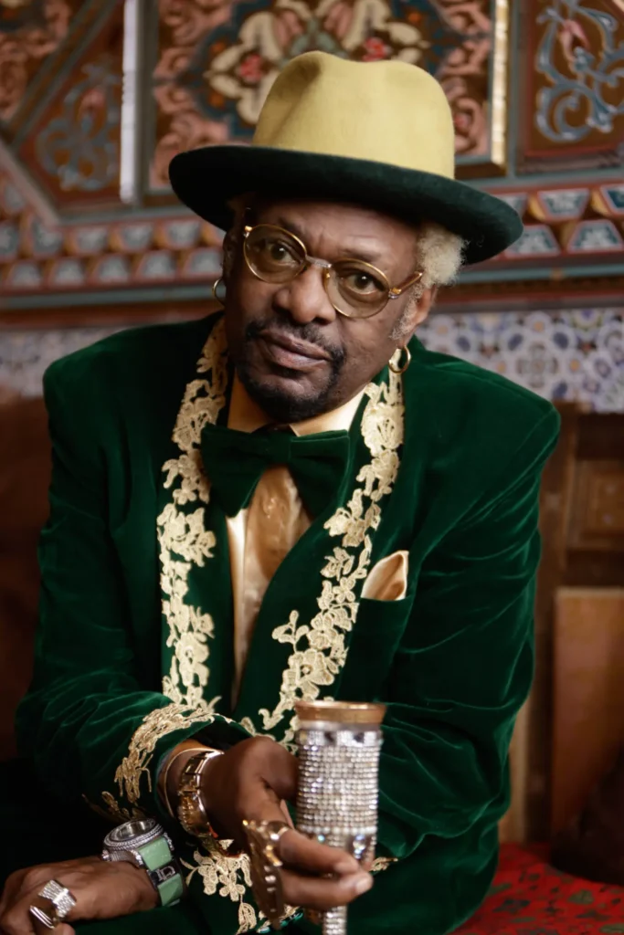 Bishop Don Magic Juan in a green velvet suit and two-tone hat