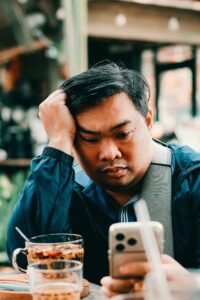 Tired man checking his phone while taking a break from dating apps