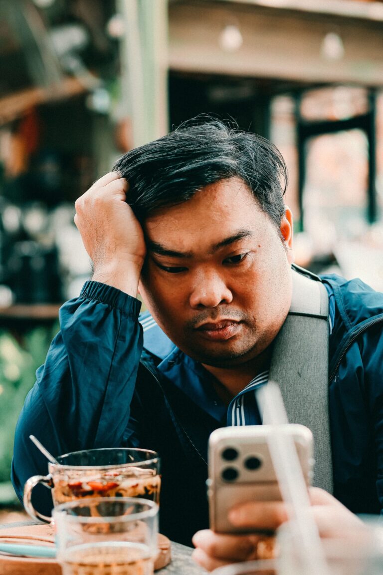 Tired man checking his phone while taking a break from dating apps