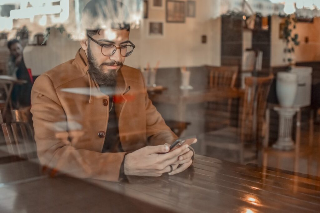 Professional man using a smartphone in a coffee shop, illustrating serious online dating