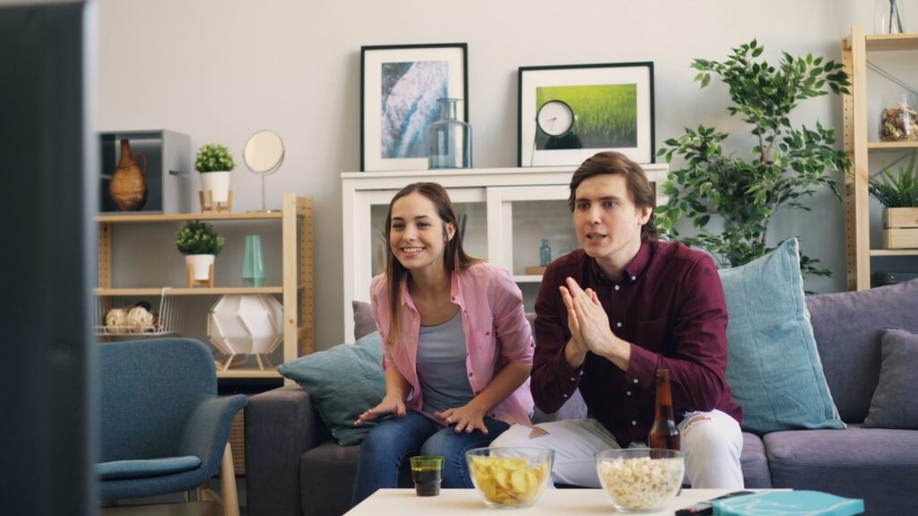 Couple sitting together in a living room, representing entertainment and dating culture