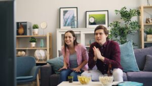 Couple sitting together in a living room, representing entertainment and dating culture