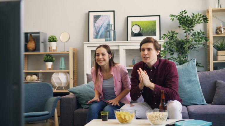 Couple sitting together in a living room, representing entertainment and dating culture