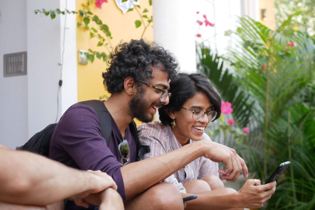 Man and woman laughing while looking at a smartphone, illustrating dating-app conversation