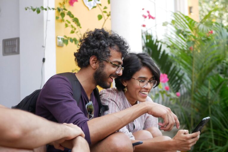 Man and woman laughing while looking at a smartphone, illustrating dating-app conversation