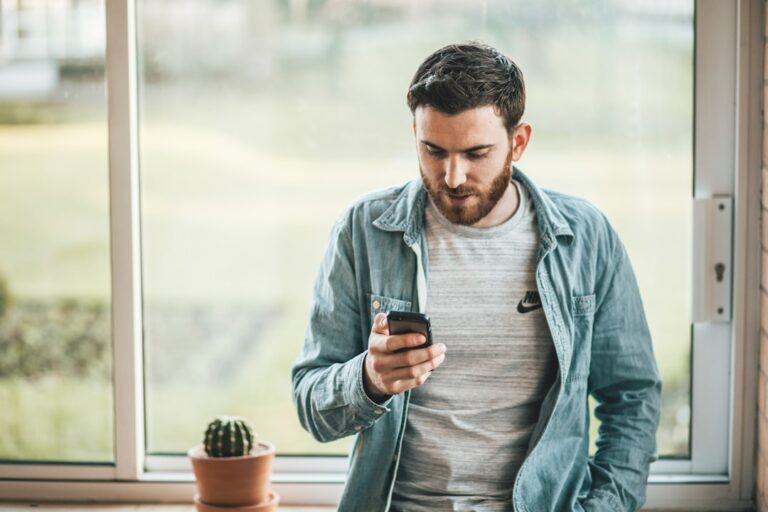 Man holding a smartphone near a window, illustrating modern online dating