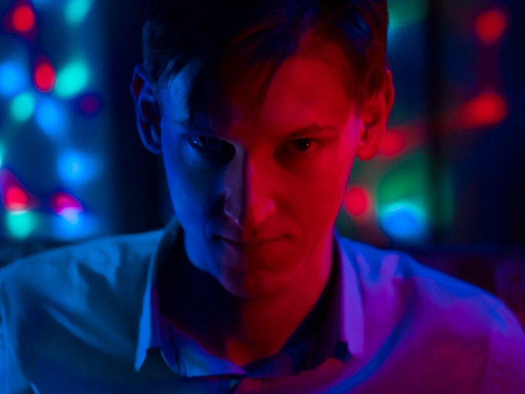 Man lit by red and blue light considering competing ideas
