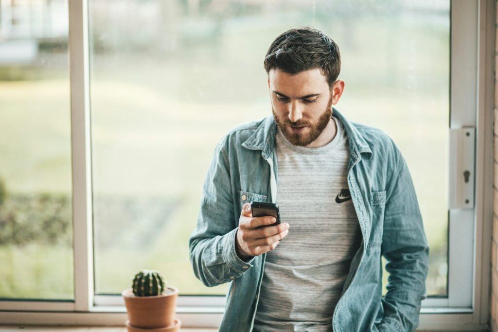 Man checking a phone while a dating app conversation loses momentum